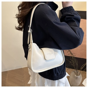 Close-up of white crescent shoulder bag featuring lychee grain leather and silver buckles