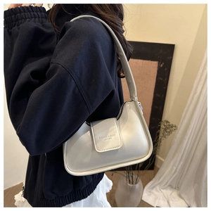 Close-up of a white leather hobo bag worn by a model in a minimalist home setting