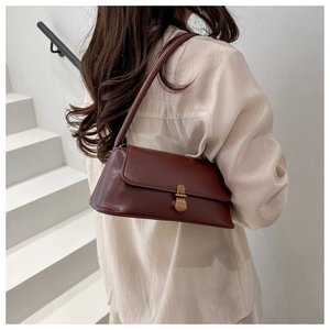 Model wearing a vintage dark brown baguette bag with a gold buckle in a minimalist setting