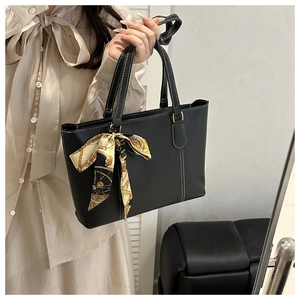 Close-up of black tote bag with white contrast stitching and elegant patterned scarf detail