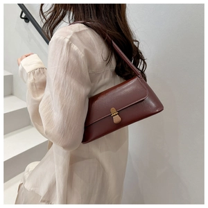 Détail du sac sous le bras bordeaux élégant avec boucle dorée vintage sur fond blanc