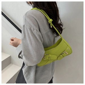Detail of green leather baguette bag with dual gold buckles and stylish knotted shoulder strap