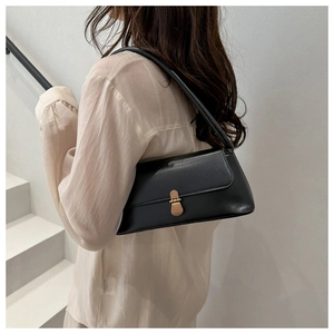 Détail d'un sac sous le bras noir rectangulaire avec fermoir doré sur le mannequin