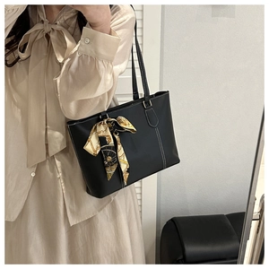 Close-up of minimalist black tote bag with white contrast stitching and silk scarf detail