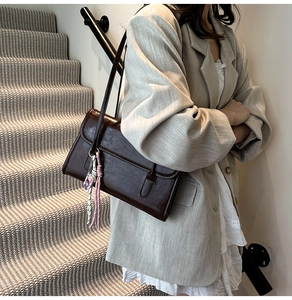 Macro detail of dark brown retro shoulder bag with textured leather and woven rope knot