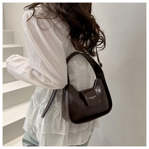 Detail of dark chocolate oil leather bag featuring fine texture and brand lettering