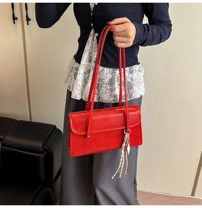 Détail du sac à bandoulière rectangulaire en cuir rouge avec breloque nœud et rabat