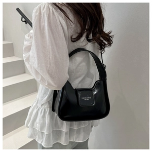 Detail of a black crescent moon shoulder bag in shiny faux leather with white text print