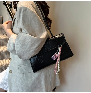 Detailed texture of black oil wax leather underarm bag with cute hanging accessories