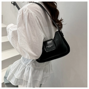 Close-up of the black leather shoulder bag with white fashion logo on a model
