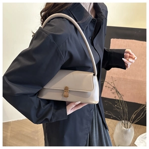 Detail of a beige leather baguette bag featuring a vintage gold push-lock buckle