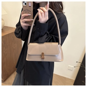 Close-up of beige baguette bag featuring a dark wood-textured turn-lock closure