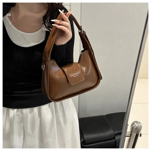 Close-up of brown glossy leather hobo bag featuring embossed Fashion & Bags lettering