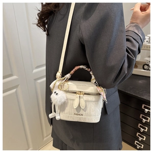 Detail of white marble textured bucket bag with silk scarf handle and plush pendant