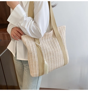 Détail du sac cabas en paille tressée avec pompon blanc et bandoulières beige