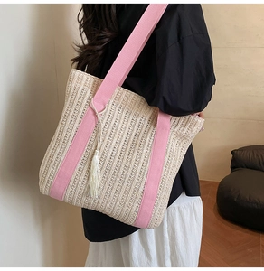 Détail du sac cabas en paille tissée avec sangles roses et décoration de gland blanc