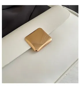 Detail of creamy white leather envelope bag with large polished gold square metal buckle
