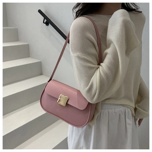 Sac à bandoulière rose avec boucle dorée porté par un mannequin dans un décor urbain