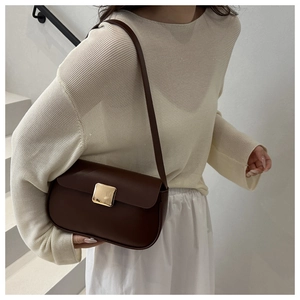 Detail of dark brown leather shoulder bag with a polished gold square metal buckle