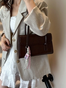 Retro dark brown rectangular shoulder bag with chic pendant shown on a model