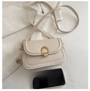 Mini crossbody bag in beige leather with golden horseshoe lock compared with a smartphone