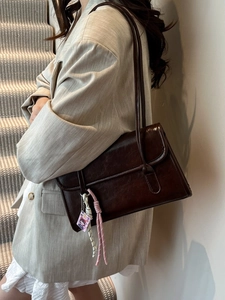 Dark brown underarm shoulder bag in wax texture faux leather with decorative pendant