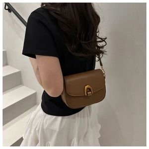 Vue détaillée du sac besace en cuir marron avec boucle fer à cheval dorée sur modèle