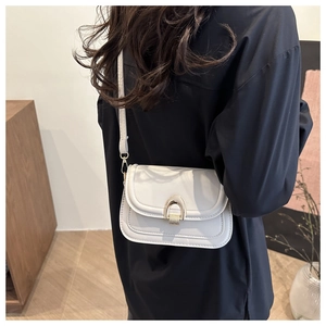 Detail of white leather crossbody bag with U-shaped gold buckle worn by model