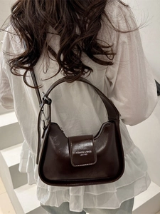 Dark brown crescent shoulder bag in glossy leather with adjustable strap shown on model