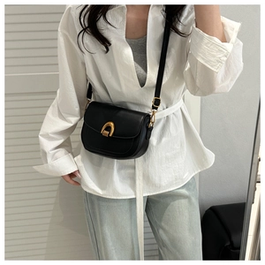 Détail du sac besace noir mat avec boucle fer à cheval dorée et bandoulière fine