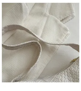 Detail of white woven leather texture with high-quality gold metal zipper on handbag