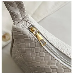 Close-up of golden metal zipper and premium woven leather texture on white shoulder bag