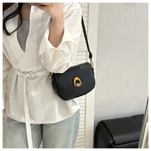 Détail du sac selle en cuir noir avec un fermoir en métal doré en forme de U élégant