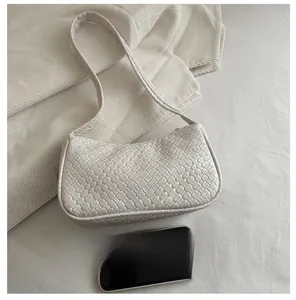 Detail of white woven hobo bag with size comparison next to a smartphone