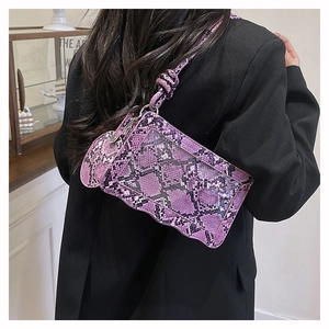 Detail view of purple snake print crossbody bag with scalloped edge on model