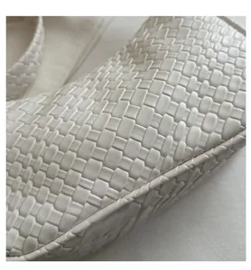 Macro view of white woven leather texture on a high-capacity shoulder bag