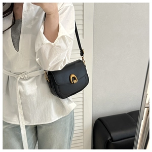 Détail du sac à selle rétro noir en cuir avec une boucle en fer à cheval dorée texturée