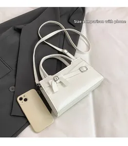 Detailed view of white leather crossbody bag with bow accent and silver metal buckle detail