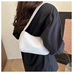 Gros plan détaillé d'un sac hobo blanc à texture tressée porté à l'épaule par un mannequin