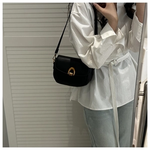 Détail du sac besace noir minimaliste avec boucle fer à cheval dorée et rabat en cuir