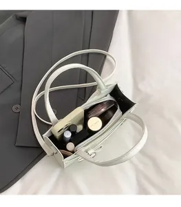 Detail view of the spacious interior of a beige square bag holding makeup and phone