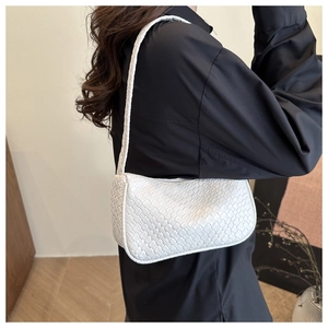 Detail of the white woven dumpling bag showing fine texture and side view on shoulder