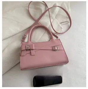 Pink mini crossbody bag detail showing bow decor and size comparison with a smartphone