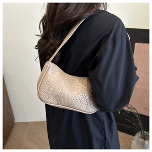 Détail du tissage sur sac hobo beige porté par un mannequin dans un cadre moderne