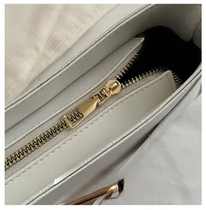 Detail view of smooth gold zipper and fine stitching on a beige leather handbag