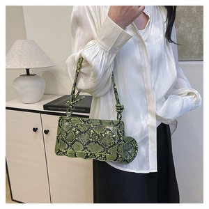 Detail of emerald green snake print crossbody bag with wave edge and round coin purse charm