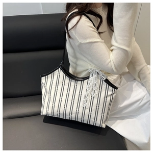 Detail of canvas tote bag with black stripes and a decorative white lace bow