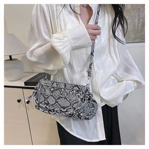 Détail du sac bandoulière à motif serpent porté avec un élégant chemisier en soie blanc