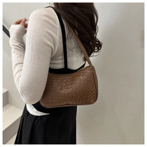 Détail de la texture tissée marron foncé d'un sac baguette porté par un mannequin