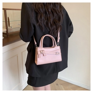Detailed view of pink crossbody bag with bow decoration and metallic ring buckle